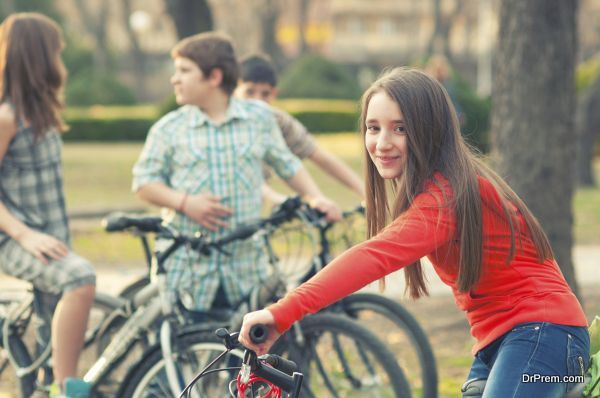 Teenage girl having fun on bicycles with her friends in the park