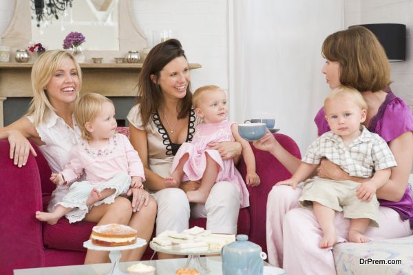 Three mothers in living room with babies and coffee smiling