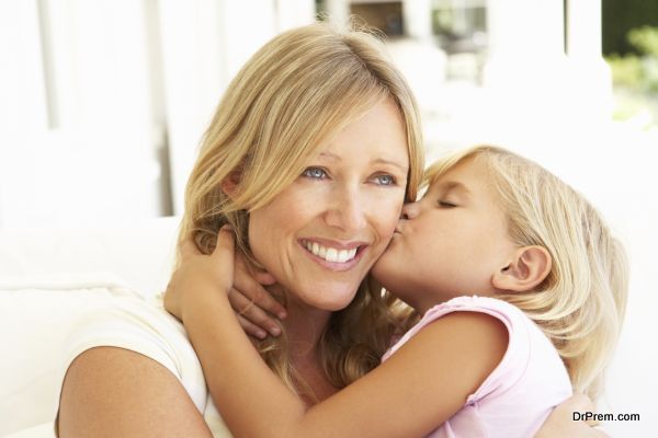 Daughter Giving Mother Kiss Relaxing On Sofa