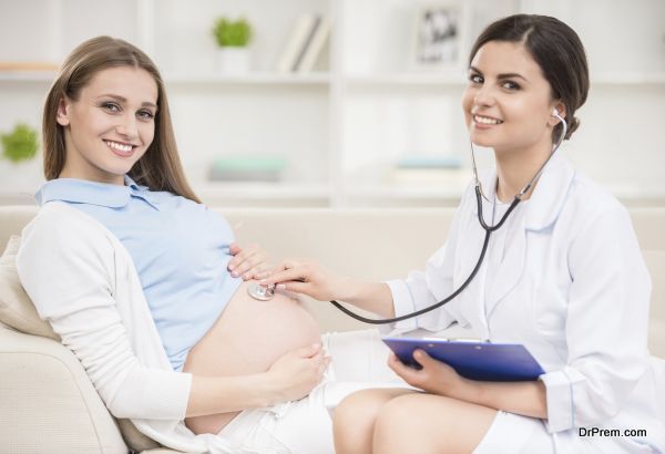 Doctor checking pregnant woman's tummy with stethoscope.