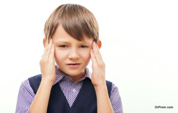 It is hard to concentrate. Closeup of stressed little boy in formal wear touching his temples with his fingers as if suffering from headache while standing isolated on white