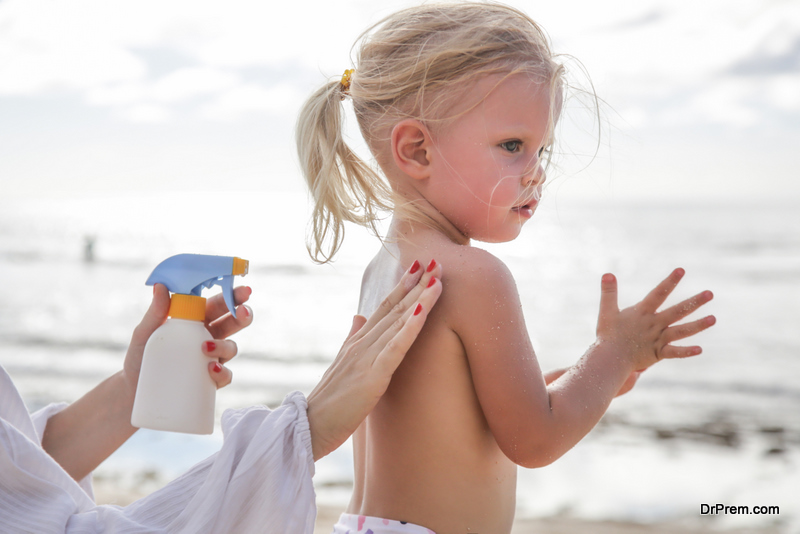 Mother applying sunscreen protection lotion on cute little toddler girl